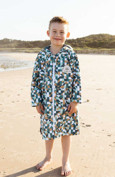 Child wearing Earth and Sky wearable towel at the beach